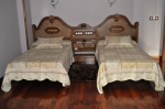 Detalle de las camas y el cabecero sobre el suelo original del piso de Don Felix Hotel en Rioseco de Sobrescobio